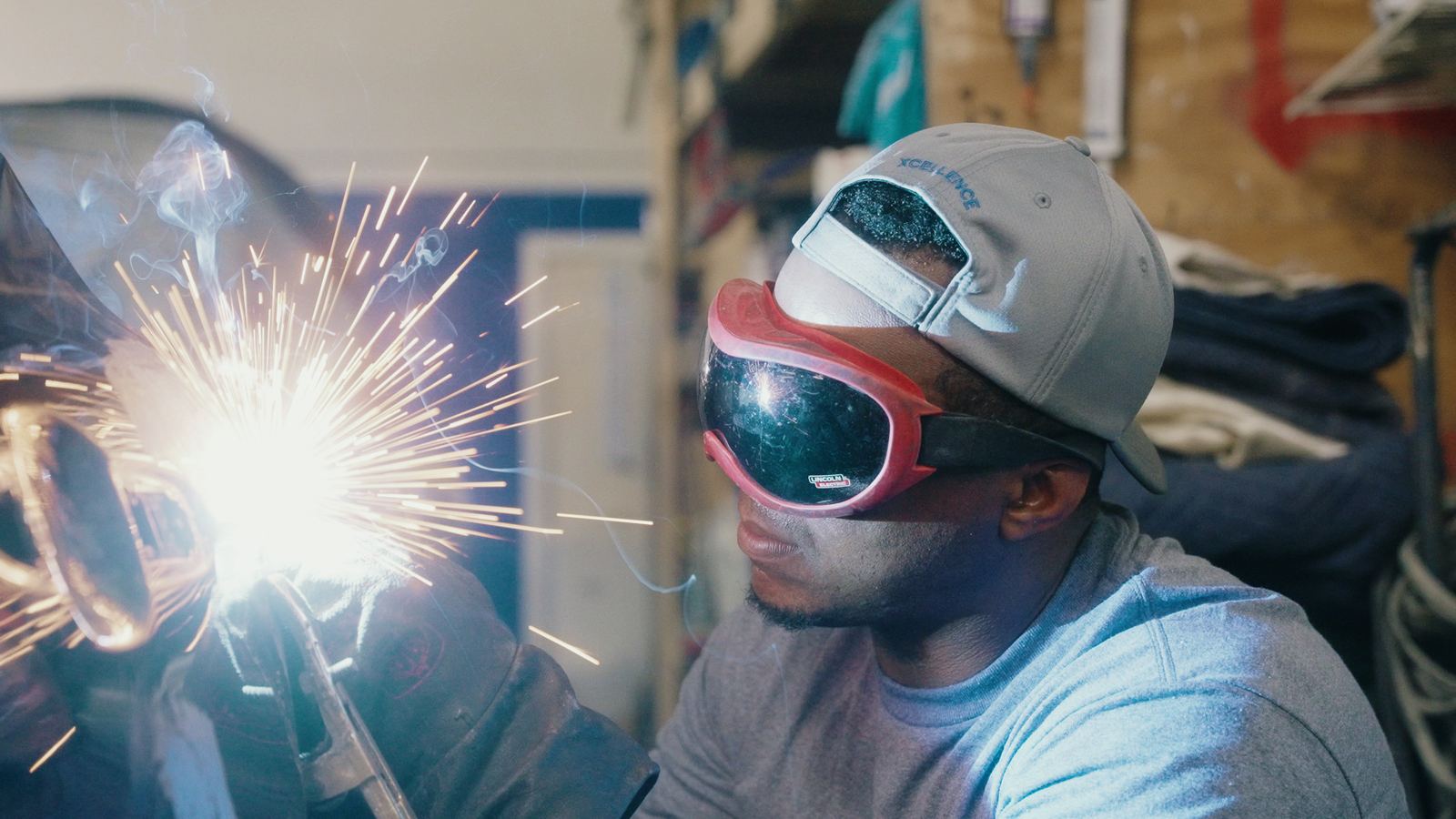Technician welding with sparks at Xcellence Body Works